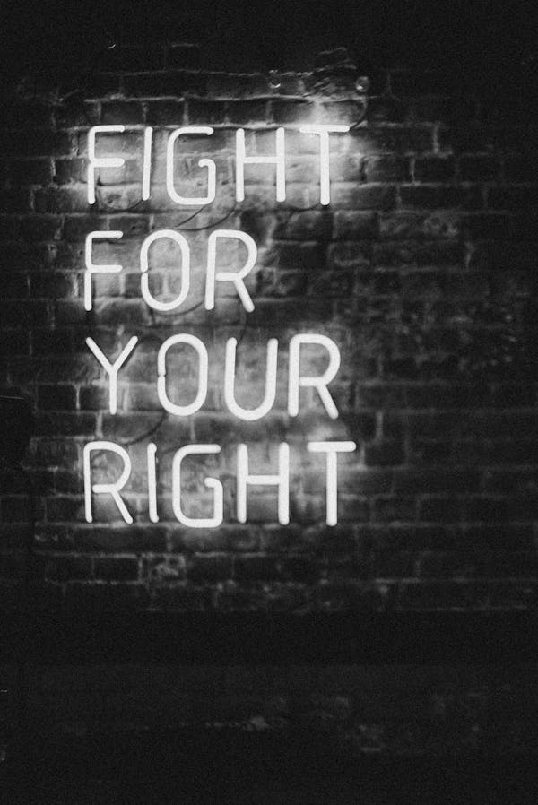 Monochrome neon sign on brick wall with slogan 'Fight for Your Right.' Perfect for motivation and urban themes.